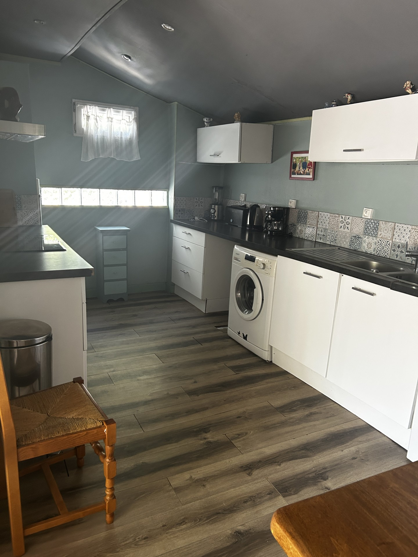 La cuisine équipée avec ses meubles blancs, son plan de travail et son lave-linge